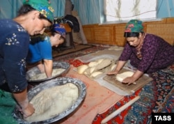 Turkmen women cook traditional loaves of bread.