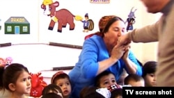 Воспитательница детского садика целует руку Бердымухамедова.
