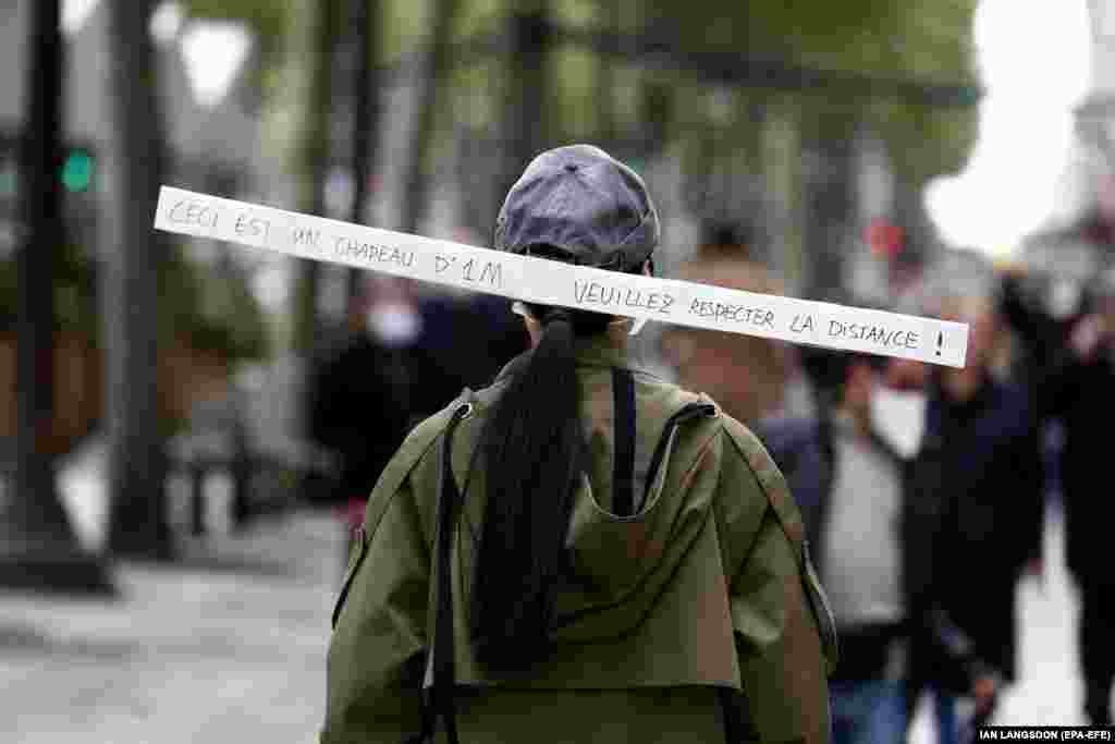 A woman wears a hat reading &#39;This is a one-meter hat. Please keep your distance&#39; as she walks along the Champs Elysee avenue in Paris, France, 11 May 2020. France began a gradual easing of its lockdown measures and restrictions amid the COVID-19 pandemic.