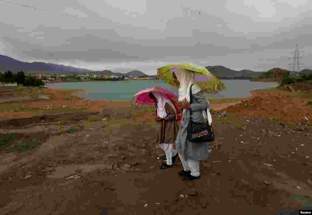 Afghan schoolgirls hold umbrellas to shelter from the rain on the outskirts of Kabul. (Reuters/Mohammad Ismail)