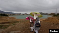 Afghan school girls hold umbrellas to shelter from rain on outskirt of Kabul on May 15.