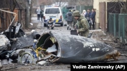 Украинский военнослужащий осматривает части сбитого самолета во время полномасштабного вторжения России в Украину. Киев, 25 февраля 2022 года