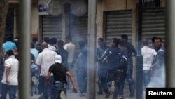 Protesters run for cover during riots in central Tunis on May 8