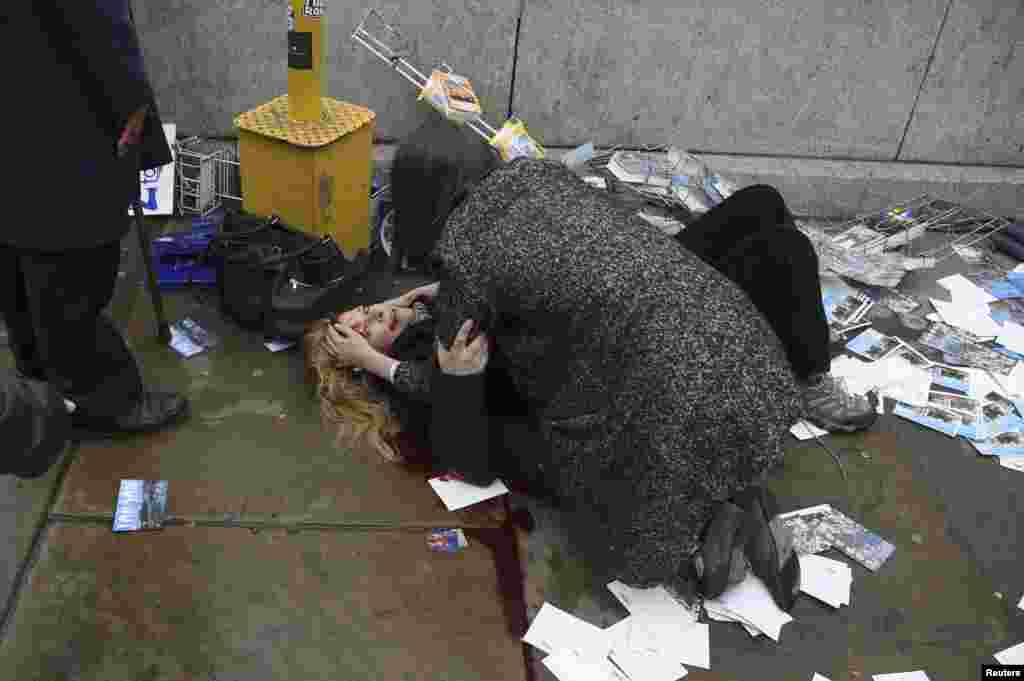 An injured woman is helped by a passerby on Westminster Bridge.