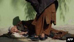 An elderly man lies on the ground as he begs in Kandahar. (file photo)