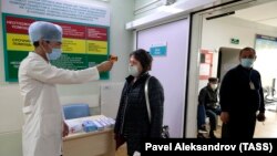 Медицина қызметкері ауруханаға келген адамдардың дене қызуын өлшеп жатыр. Алматы, наурыз айы 2020 жыл. 