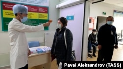 Медицина қызметкері ауруханаға келген адамның қызуын тексеріп тұр. Алматы, 26 наурыз 2020 жыл.