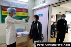 Медицинский работник с помощью термометра измеряет температуру посетителя в больнице в Алматы, 26 марта 2020 года.
