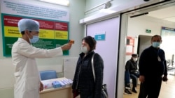 A medical worker uses a forehead thermometer to screen the temperature of a visitor in an Almaty hospital.