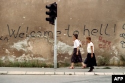 Două femei pe așa-numita „Aleea Snaiperilor” din Sarajevo, la 24 august 1993. „Bine ați venit în iad!”, proclamă inscripția în engleză de pe zid