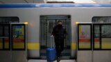 Beijing, China - A man wearing a face mask walks out of the subway with a suitcase in the morning after the extended Lunar New Year holiday caused by the novel coronavirus outbreak, at the Xierqi subway station