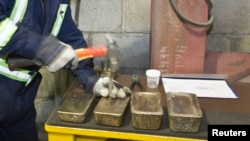 Работник кыргызского завода маркирует золотые слитки. 14 марта 2013 года.