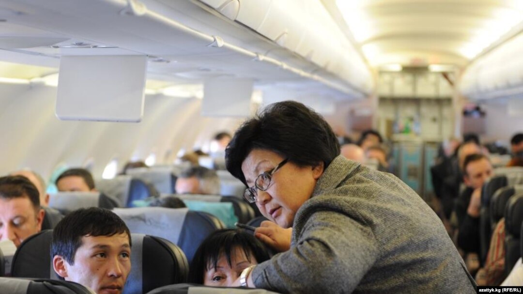 Her spokesman says Otunbaeva (standing) could often be seen on commercial flights mingling with the other passengers.