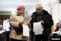 A man and a woman study their ballots as they visit a polling station during local elections in Kyiv on October 25.