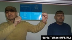 Қазақстан конституциясын көрсетіп тұрған Макс Боқаев пен Талғат Аян (оң жақта) сот процесі кезінде. Атырау, 18 қазан 2016 жыл.