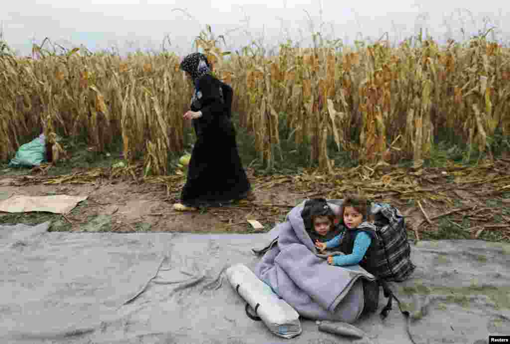 Children rest on the ground next to a cornfield as migrants wait to enter Croatia from Berkasovo, Serbia. (Reuters/Antonio Bronic)