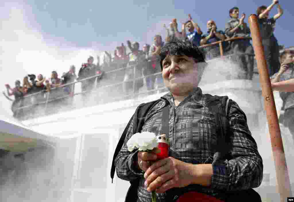 A Romanian woman holds flowers and a candle to pay tribute to Dinamo's Cameroonian midfielder Patrick Claude Ekeng during a ceremony at Dinamo Stadium in Bucharest. Ekeng collapsed during a Romanian Premier Soccer League playoff match between Dinamo Bucharest and Victoria in Bucharest on May 6. Ekeng fell unconscious without being touched by any other player and died at hospital hours later from a suspected heart attack. He was 26. (epa/Robert Ghement)