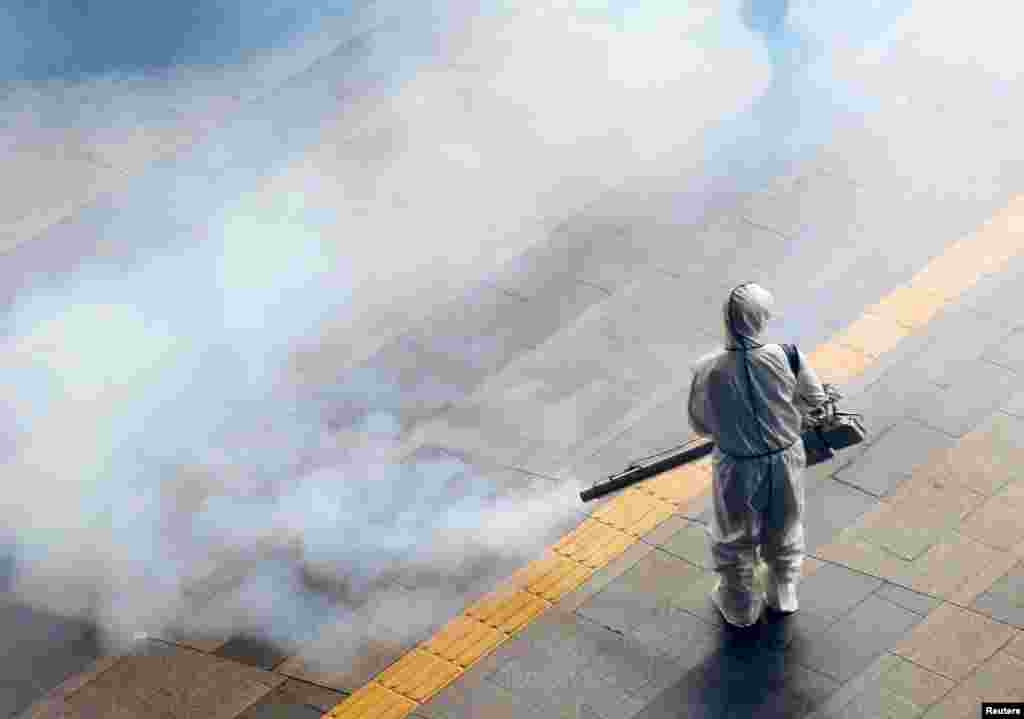 Робітник епідемологічної служби в захисному костюмі дезінфікує підлогу станції метро в Сеулі