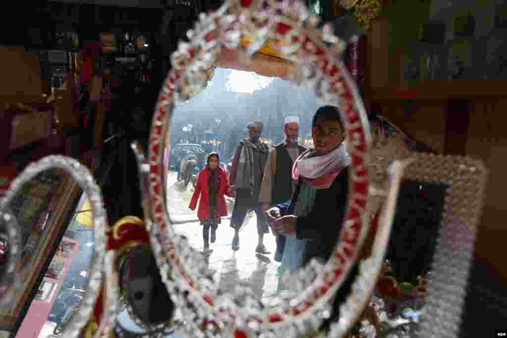 Afghans are reflected in mirrors for sale on a shop in Herat. (epa/Jalil Rezayee)