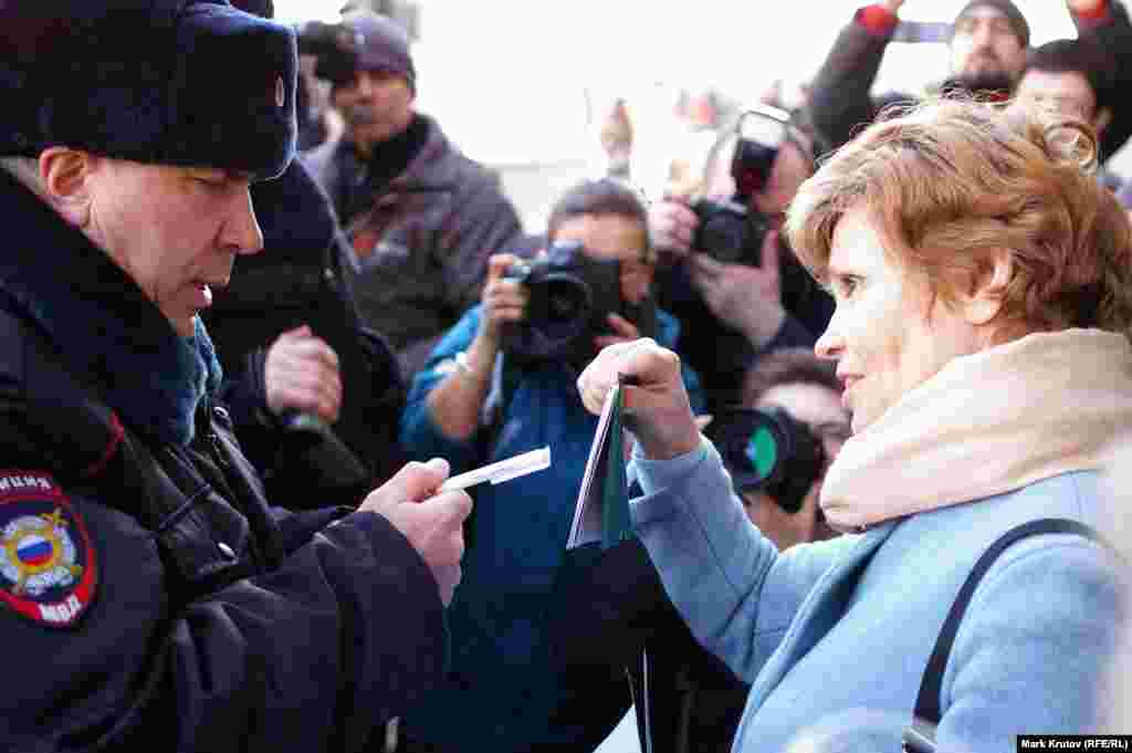 Женщина, стоявшая в пикете, показывает полицейским свой паспорт