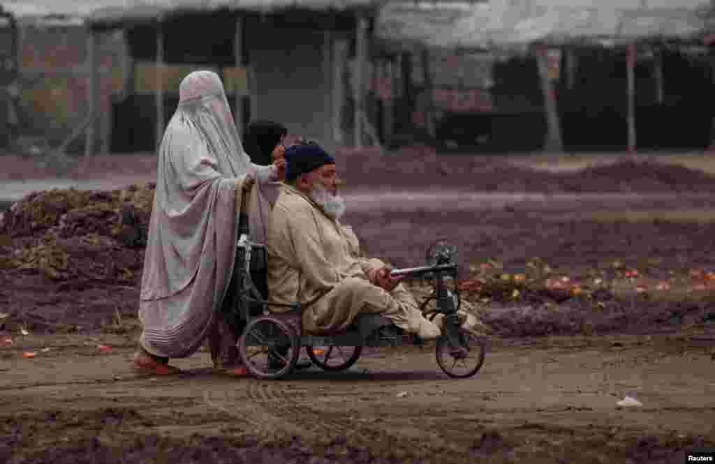 A family helps a disabled man with his wheelchair on a roadside outside Peshawar, Pakistan. (Reuters/Fayaz Aziz)