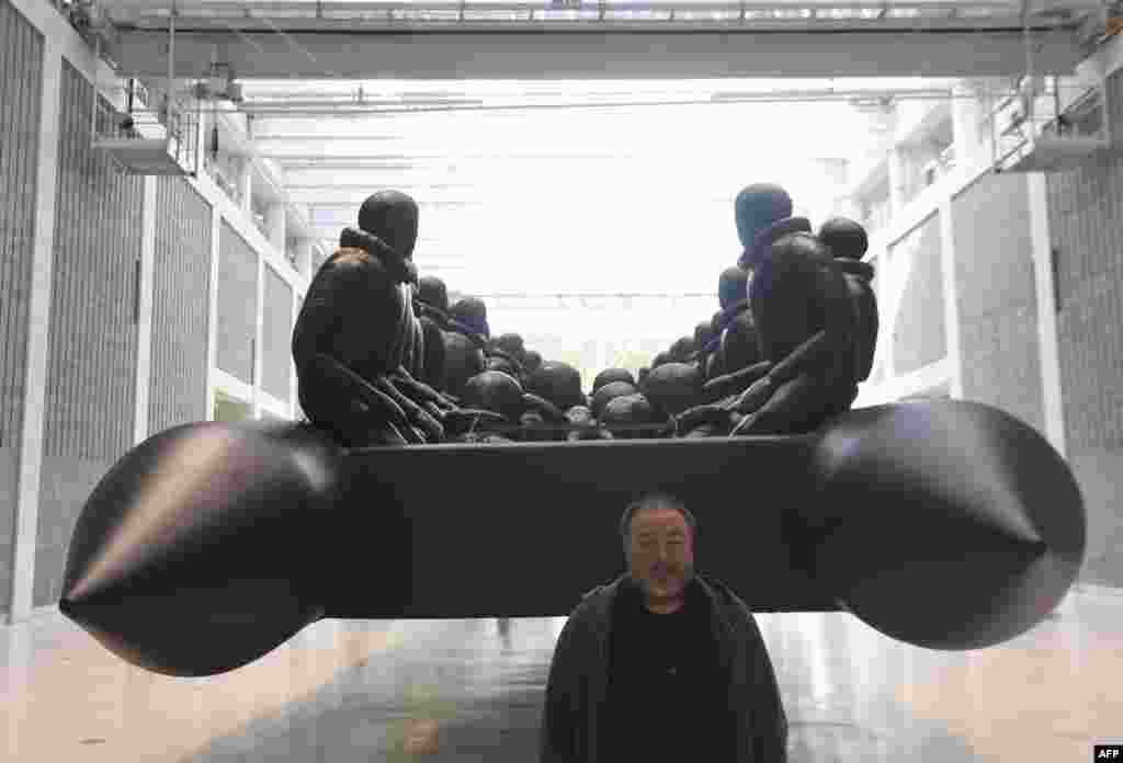 Chinese conceptual artist and political activist Ai Weiwei poses for photographers during a press conference about his new exhibition at the National Gallery in Prague. The work is called Law Of The Journey and is a 70-meter-long inflatable boat with 258 oversize refugee figures. (AFP/Michal Cizek)