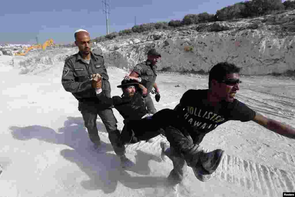 Israeli border police and private-security personnel carry an ultra-Orthodox protester during clashes in the town of Beit Shemesh, near Jerusalem. Ultra-Orthodox protesters broke into a construction site to prevent work from taking place at a site they believe contains ancient graves. (Reuters/Baz Ratner)