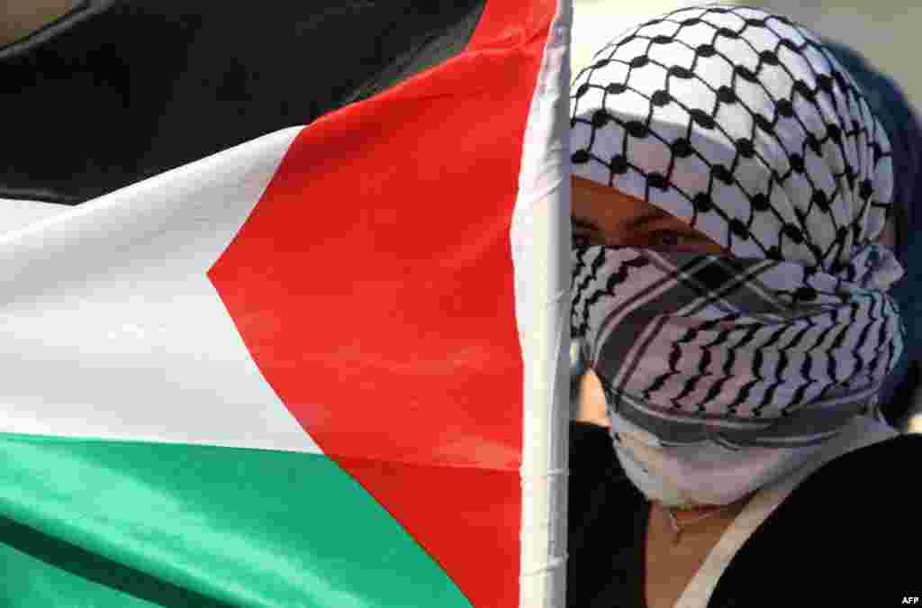 Palestina - Maskirani palestinac u blizini izraelskih vojnika na protestima protiv izraelske vojne operacije u Gazi, 15. novembar 2012. Foto: AFP / Jaafar Ashtiyeh
