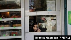 Tbilisidəki məktəbli qız öz valideynlərinin dükanında onlara kömək edir. Fotoqraf Gvantsa Gagnidze deyir: “Qız indicə bir kişiyə tort satıb. O, uzaqlaşan həmin kişinin arxasınca baxır”