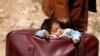 A Syrian child sleeps in a bag in the village of Beit Sawa, eastern Ghouta, as his family flees the area on March 15, 2018.
