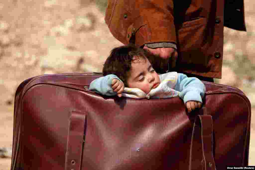 A child sleeps in a suitcase in the village of Beit Sawa, eastern Ghouta, Syria. A war monitor said that almost 20,000 civilians fled the Syrian town of Hammuriyeh and its surrounding areas in the rebel enclave of Eastern Ghouta. (Reuters/Omar Sanadiki)