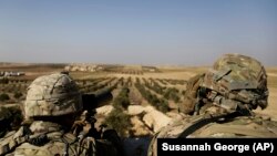 U.S. troops look toward the border with Turkey from a small outpost near the town of Manbij in northern Syria on February 7.