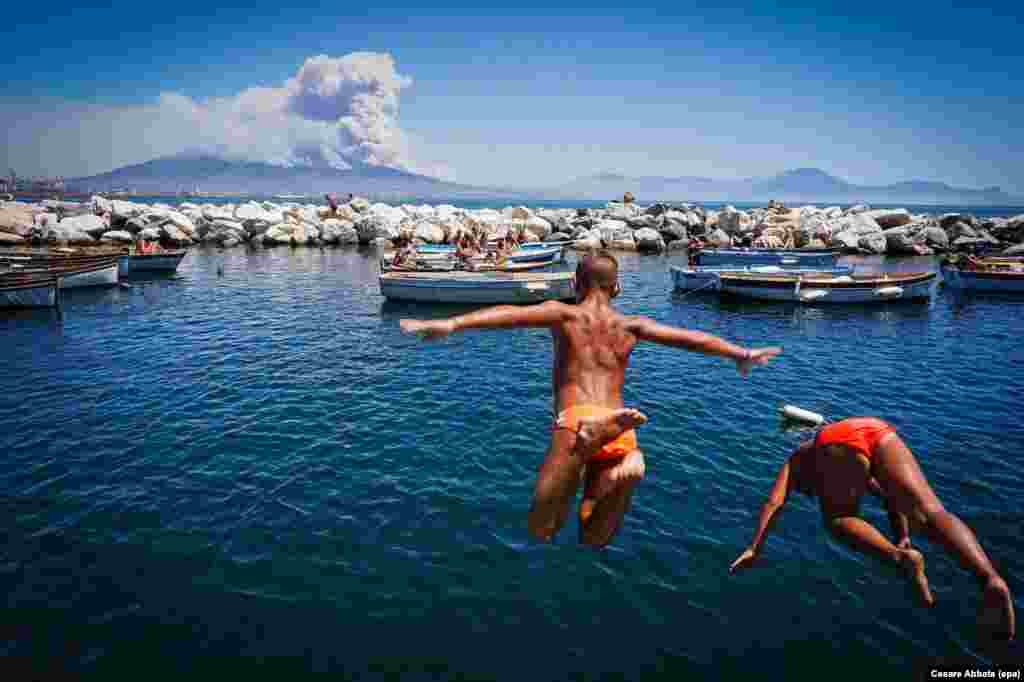 &nbsp;Children jump into the sea as smoke billows from fires around the Mount Vesuvius volcano in Naples, Italy, on July 11. (epa/Cesare Abbate)