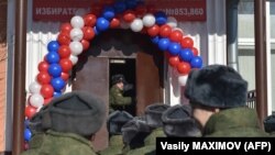 Российские военнослужащие стоят в очереди на входе на избирательный участок