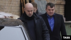 Former Defense Minister Anatoly Serdyukov (right) arrives by a back entrance for questioning by investigators in Moscow in December 2013.