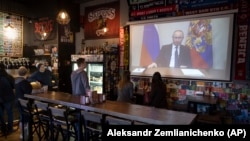 Посетители и работники паба в Москве смотрят обращение Владимира Путина к россиянам, 25 марта 2020 года