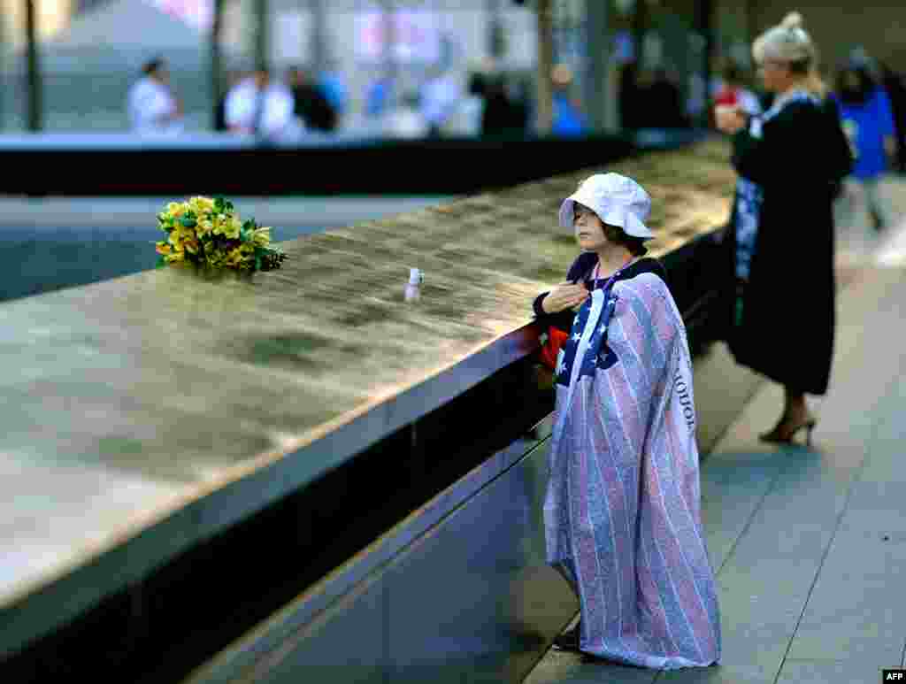 Ava Kathleen Schmoelzer, age 7, places flowers by the memorial pool at the World Trade Center site in memory of her aunt during commemorations on the eleventh anniversary of the attacks.