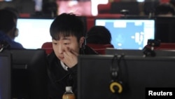 Молодой китаец сидит за компьютером в интернет-кафе. Иллюстративное фото.