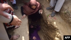 FILE: Afghan women activists weep and lie in the grave of Afghan woman Farkhunda, 27, who was lynched by an angry mob in Kabul in March 2015.