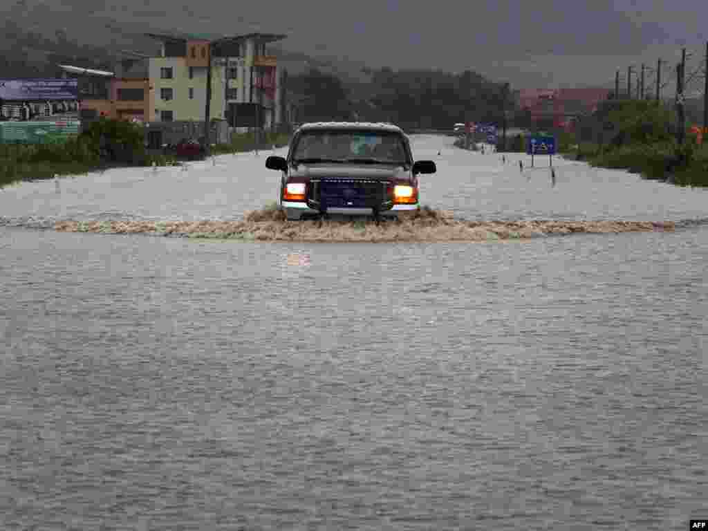 A car travels on a flooded road near the village of Jucu in Cluj, in the central Transylvania region of Romania, on June 23. (Photo by Mircea Rosca/AFP)