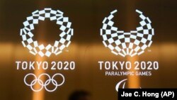 JAPAN -- A man walks past the Tokyo 2020 Olympic logos, in Tokyo, June 11, 2019