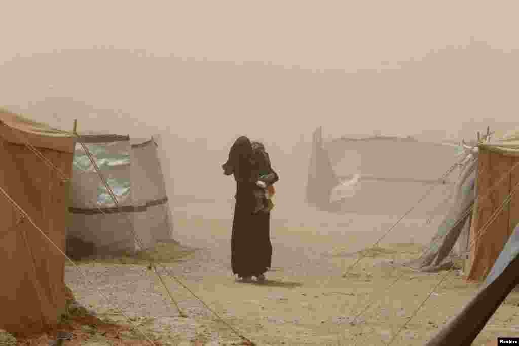 A woman who fled Fallujah because of Islamic State violence carries her child during a dust storm at a refugee camp in Ameriyat Fallujah, south of Fallujah, Iraq. (Reuters/Ahmed Saad)