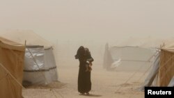 Një grua me fëmijën e saj duke u larguar nga një stuhi e pluhurit në Irak. Fotografi nga arkivi.