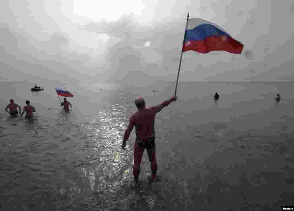 А так отмечали Крещение в другом городе полуострова, Евпатории - хотя фото мужчины в плавках с российским флагом в руках, наверное, могло бы иллюстрировать практически любой другой праздник в Крыму