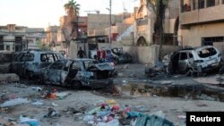 Residents walk through the site of a car bomb attack in eastern Baghdad. 