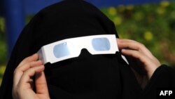 Күннің тұтылуын көзәйнектен қызықтап қарап тұрған сауд арабиялық әйел. Джидда, 15 қаңтар 2010 жыл