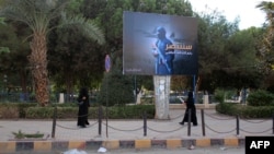 Women wearing a niqab, a type of full veil, walk under a billboard erected by the Islamic State (IS) group as part of a campaign in the IS-controlled Syrian city of Raqqa on November 2.