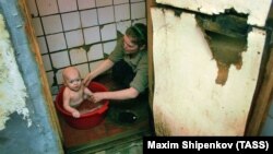 Женщина купает ребенка в общежитии