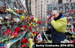 A man places flowers at the memorial to the Heavenly Hundred in Kyiv on February 20.
