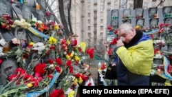 Čovek ostavlja cveće na memorijalu posvećenom Nebeskoj stotini u Kijevu, 20. februar 2019.